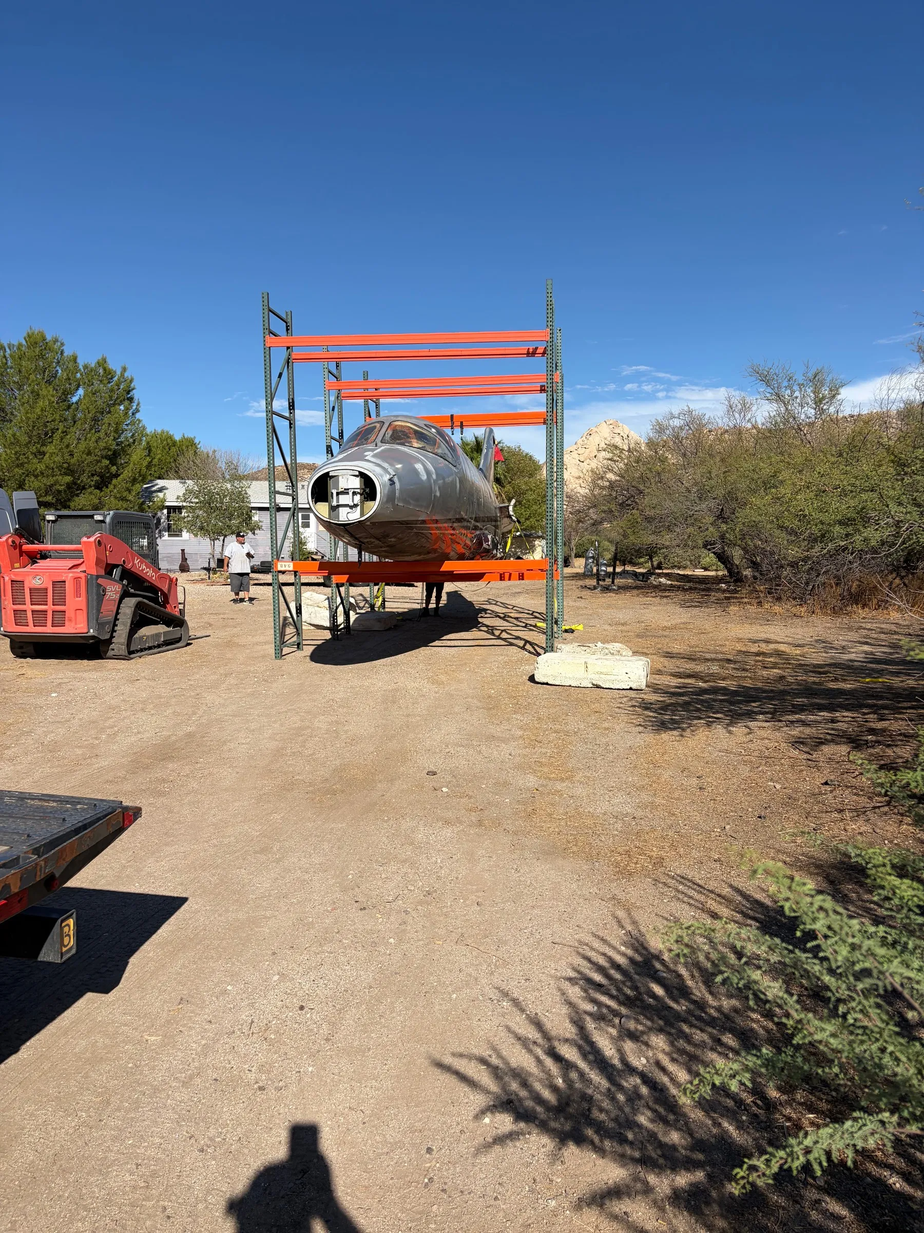 The front of the aircraft fuselage supported by a steel frame at the build location.